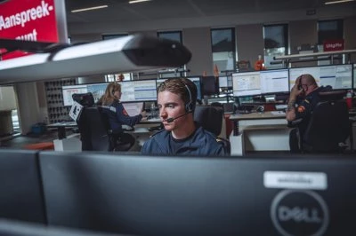 Jongeman met headset werkt geconcentreerd aan een bureau in de meldkamer.