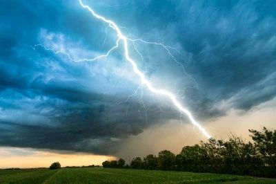 Donkere wolken met een bliksemschicht aan een bosrand