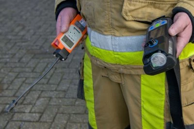 Een brandweerman houdt twee meetinstrumenten vast, met betrekking tot mogelijk gaslek