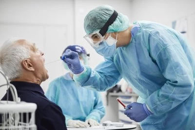 Medisch personeel in beschermende kleding neemt mond test af