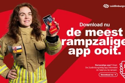 Vrouw in brandweerkleding houdt een smartphone vast tegen een rode achtergrond.