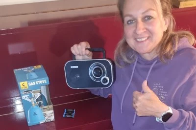 Vrouw houdt een radio vast en geeft een duim omhoog, met een doos ernaast.