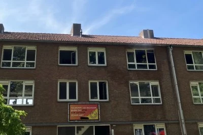 Verschillende ramen van een stenen gebouw met een heldere blauwe lucht en bomen.