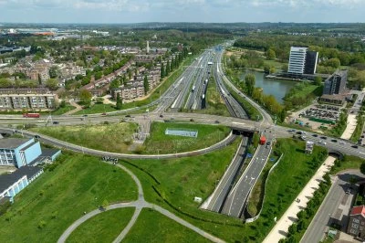 Luchtfoto van een verkeersknooppunt met groene ruimtes en moderne gebouwen.
