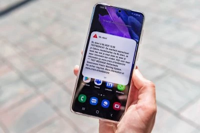 Een hand houdt een smartphone met een waarschuwing op het scherm.