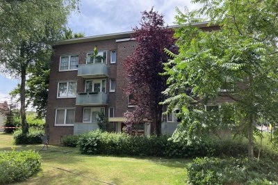 Moderne bakstenen appartementen omringd door groene bomen en struiken.