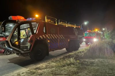 Brandweerwagens staan geparkeerd langs een weg in de nacht, verlicht door straatlantaarns.