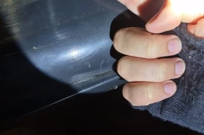 Een hand met een opgestoken vinger, verlicht door een zaklamp, wijst naar een auto.