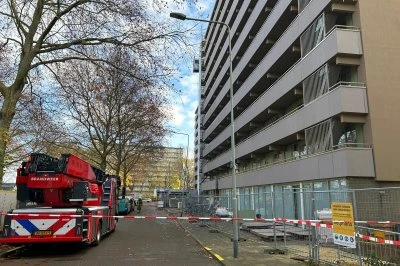 Op deze foto staat een brandweerwagen bij een met lint afgezet appartementencomplex